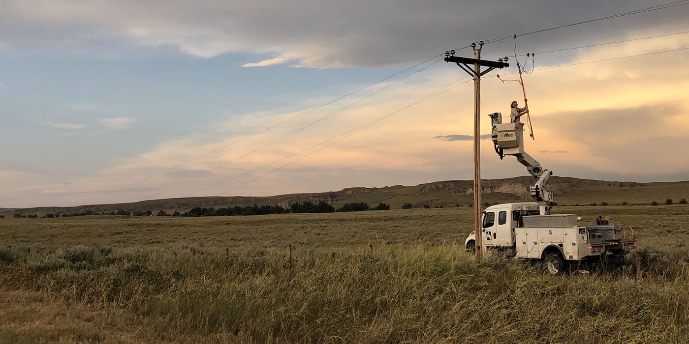 Lineman in bucket truck repairing power line at sunset